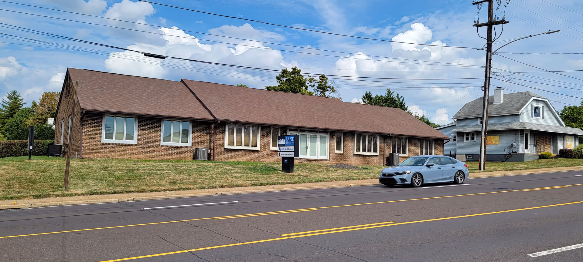 Arcadia Home Care and Staffing facility on street, brick building with a sign and parked car.