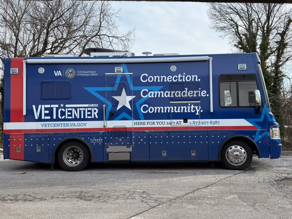 A blue Vet Center mobile bus parked outdoors with bold white lettering.