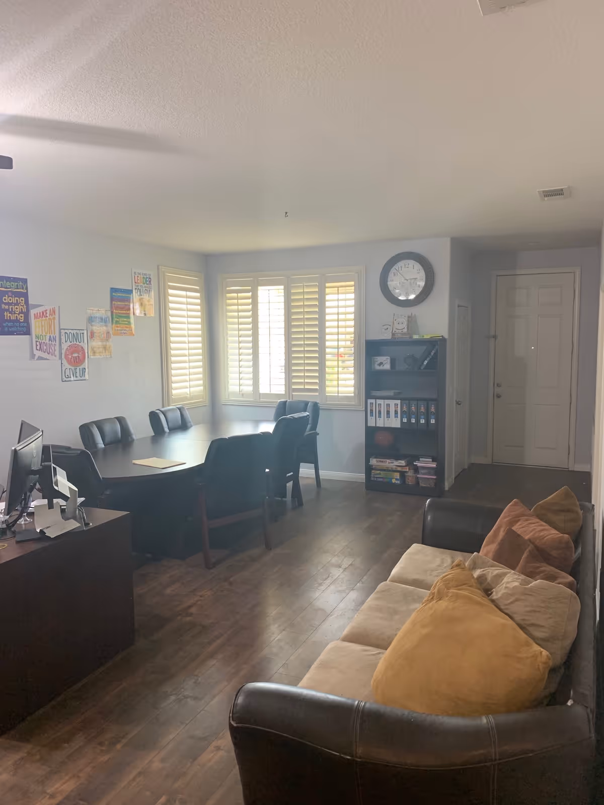 Interior common area with a long conference table, chairs, sofa, bookshelf, and windows.