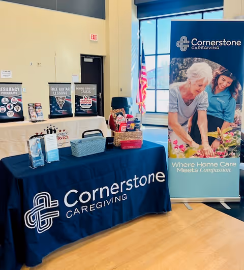Indoor lobby area featuring a Cornerstone Caregiving display table and promotional banners.