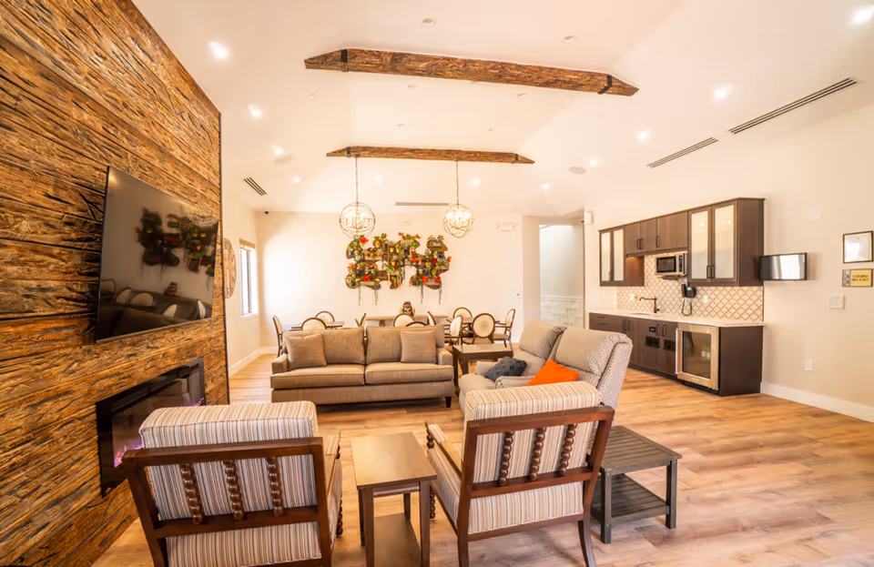 Bright open living area with a wood accent wall, sofa seating, fireplace, and kitchenette.