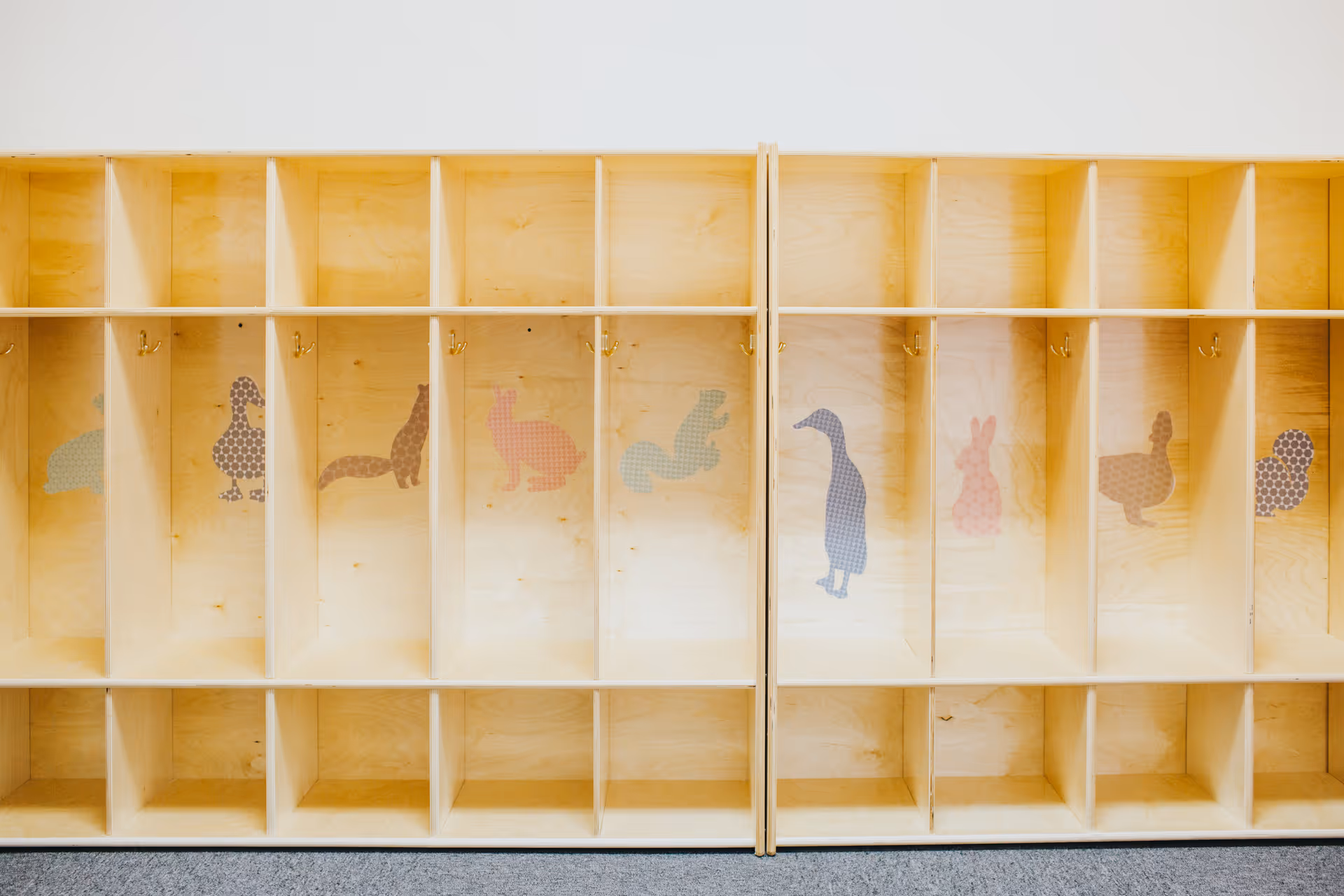 Row of wooden cubbies with animal silhouettes on interior wall.