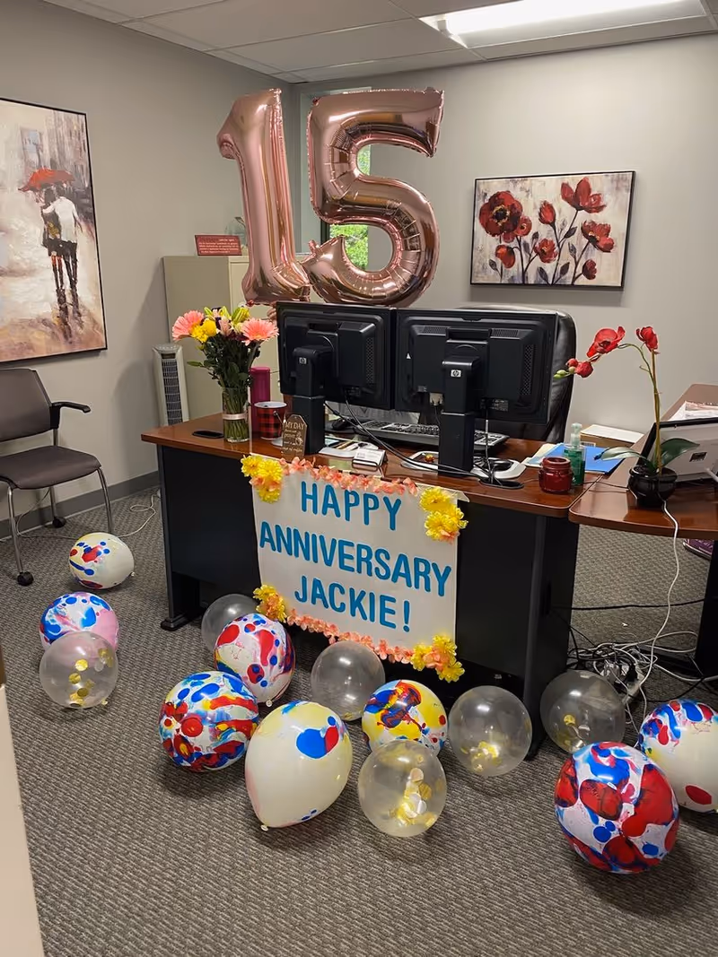 Reception desk decorated with balloons and a banner reading Happy Anniversary Jackie!