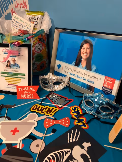 Colorful nurse-themed desk display with masks, photos, and a 'Trust me, I'm a nurse' sign.