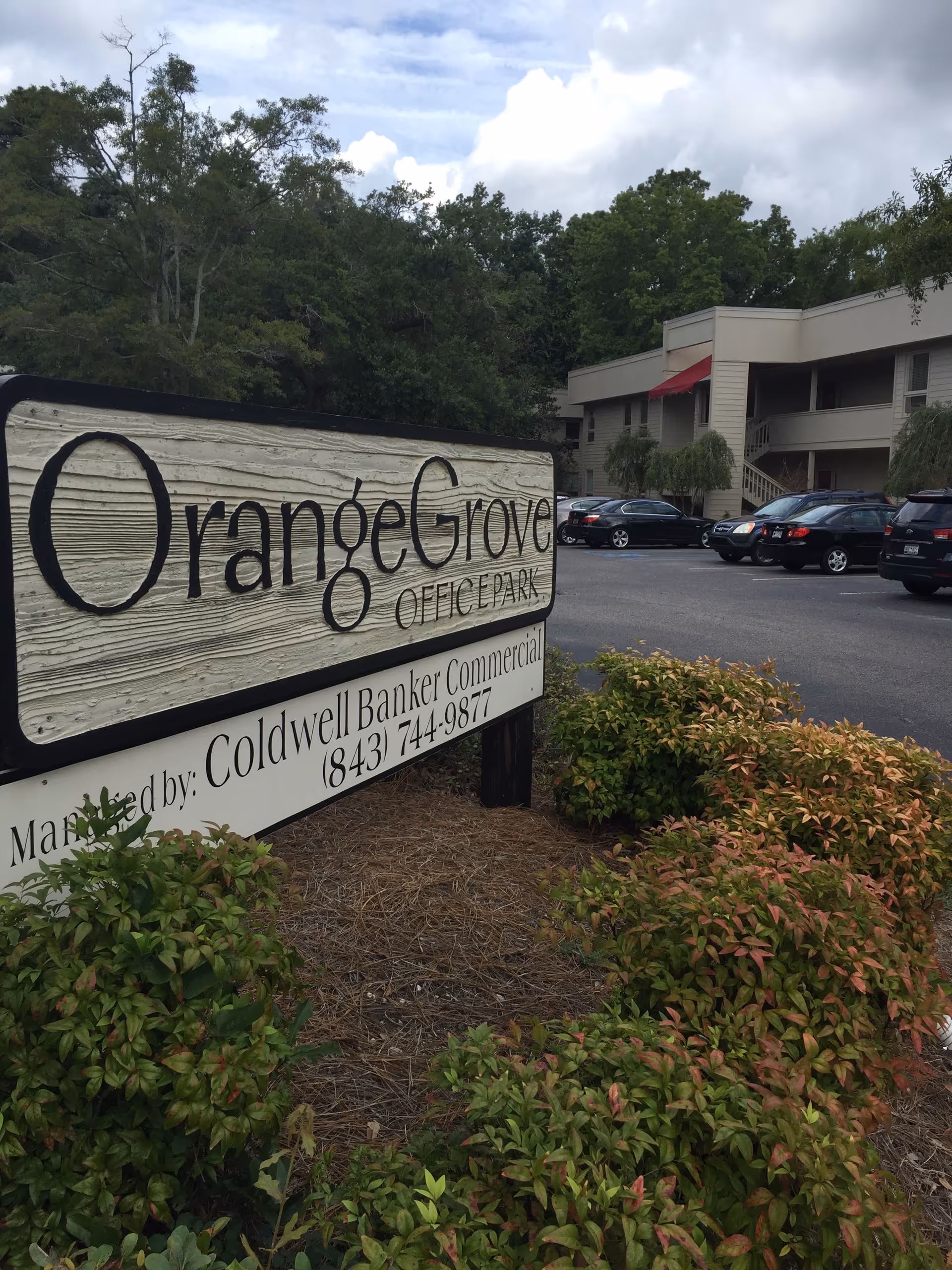 Outdoor view of a sign for Orange Grove Office Park near a parking lot and building