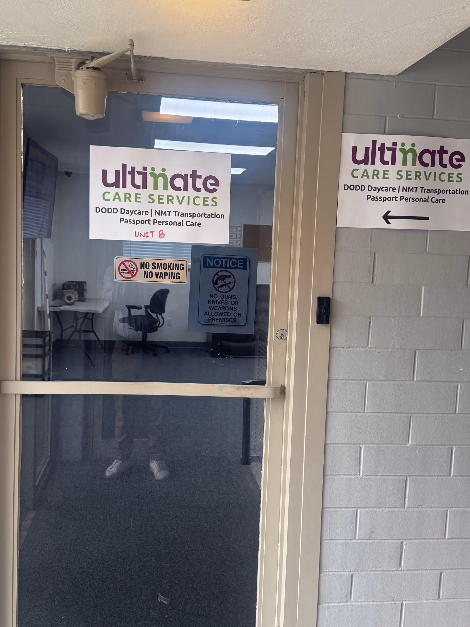 Interior entry door with Ultimate Care Services signs and notices in a hallway.