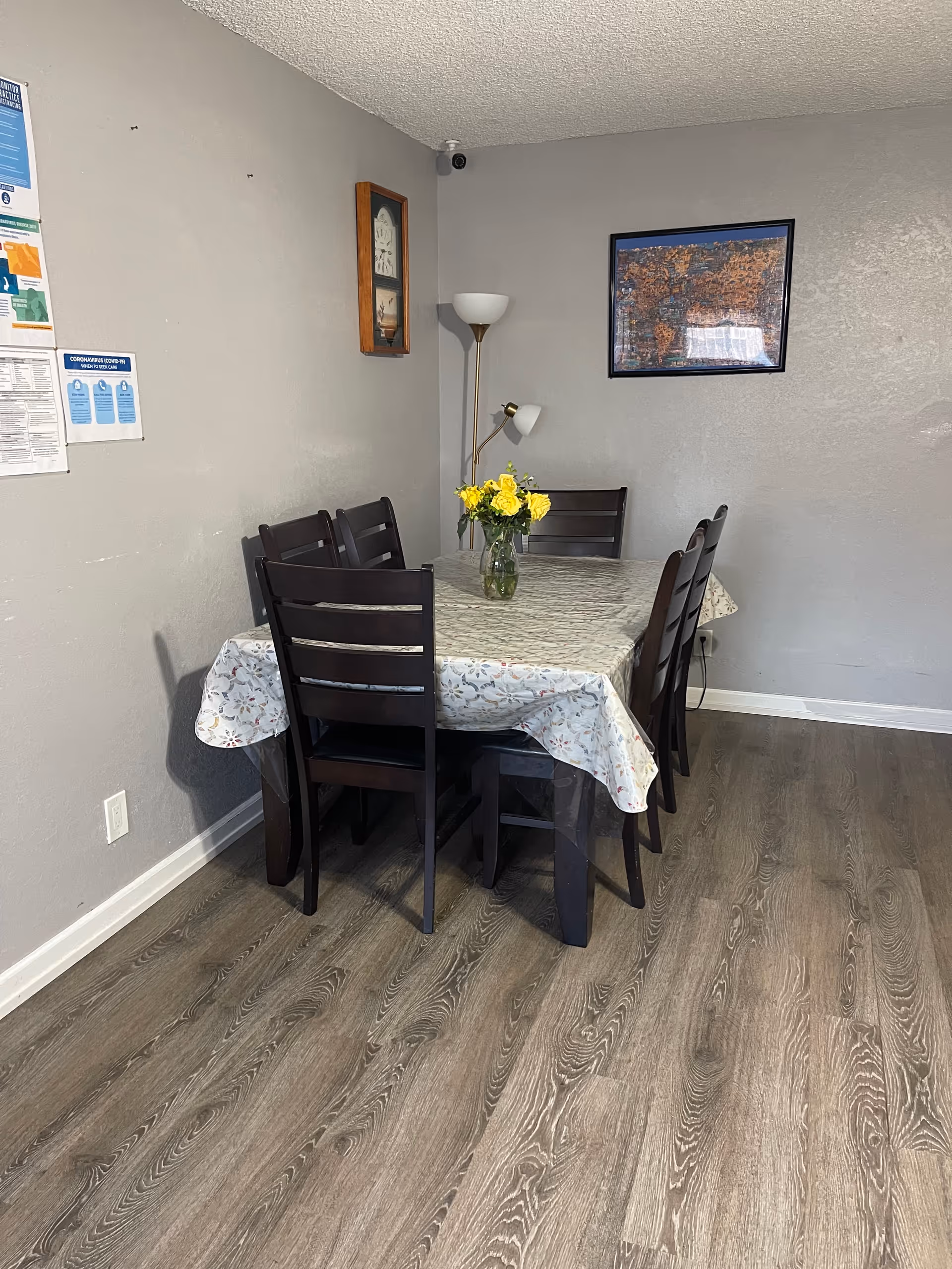 Dining room in a senior living facility with a table, chairs, and yellow flowers.