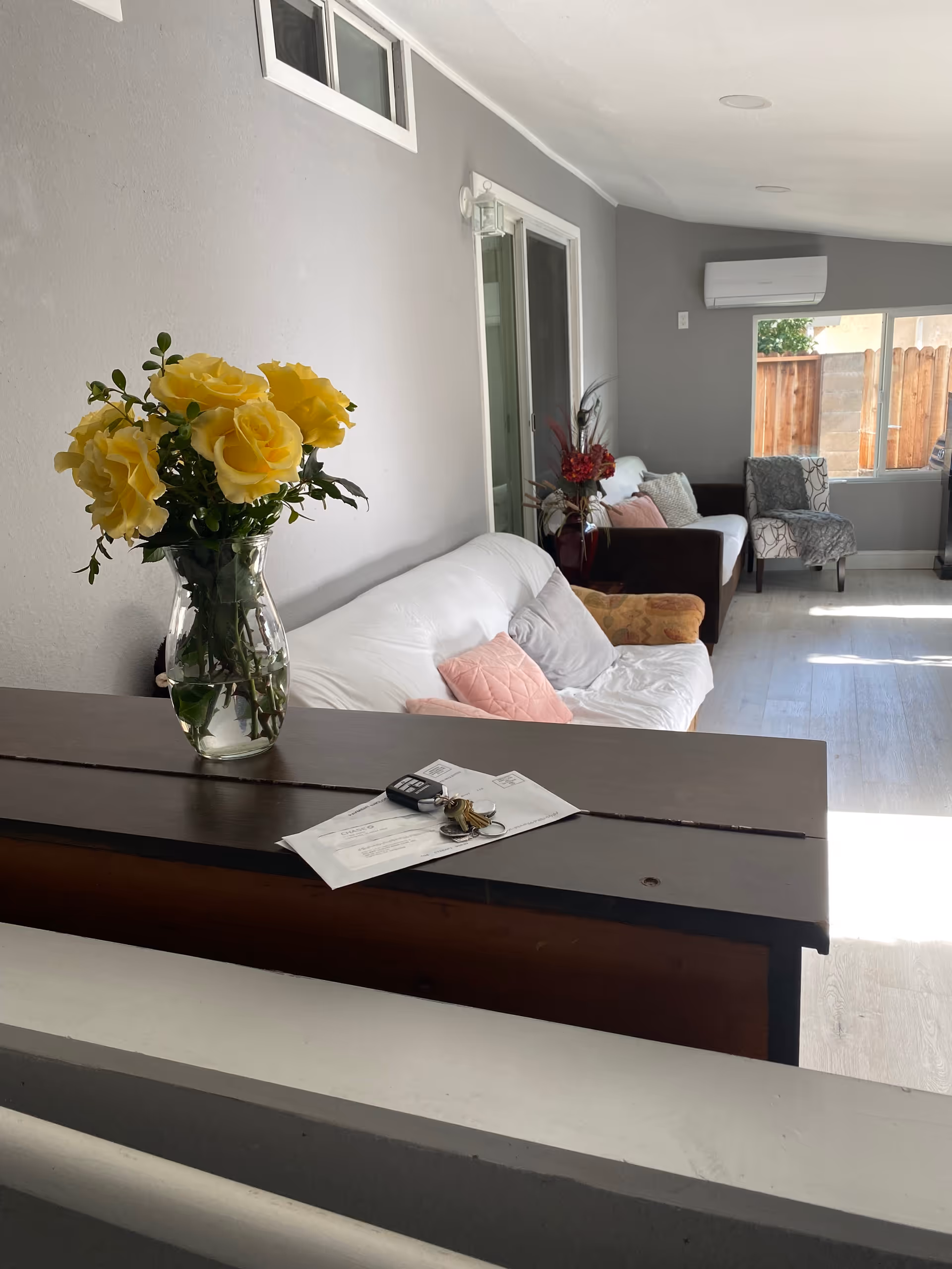 Bright living room with white sofa, chairs, yellow flowers, and a reception counter.