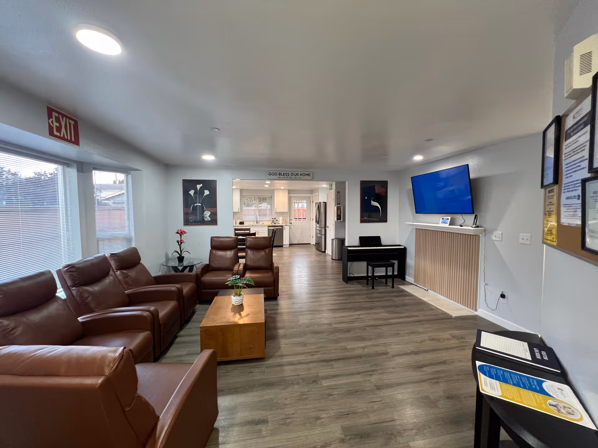 Cozy lounge area in a senior living facility with brown leather seating and a wall-mounted TV.