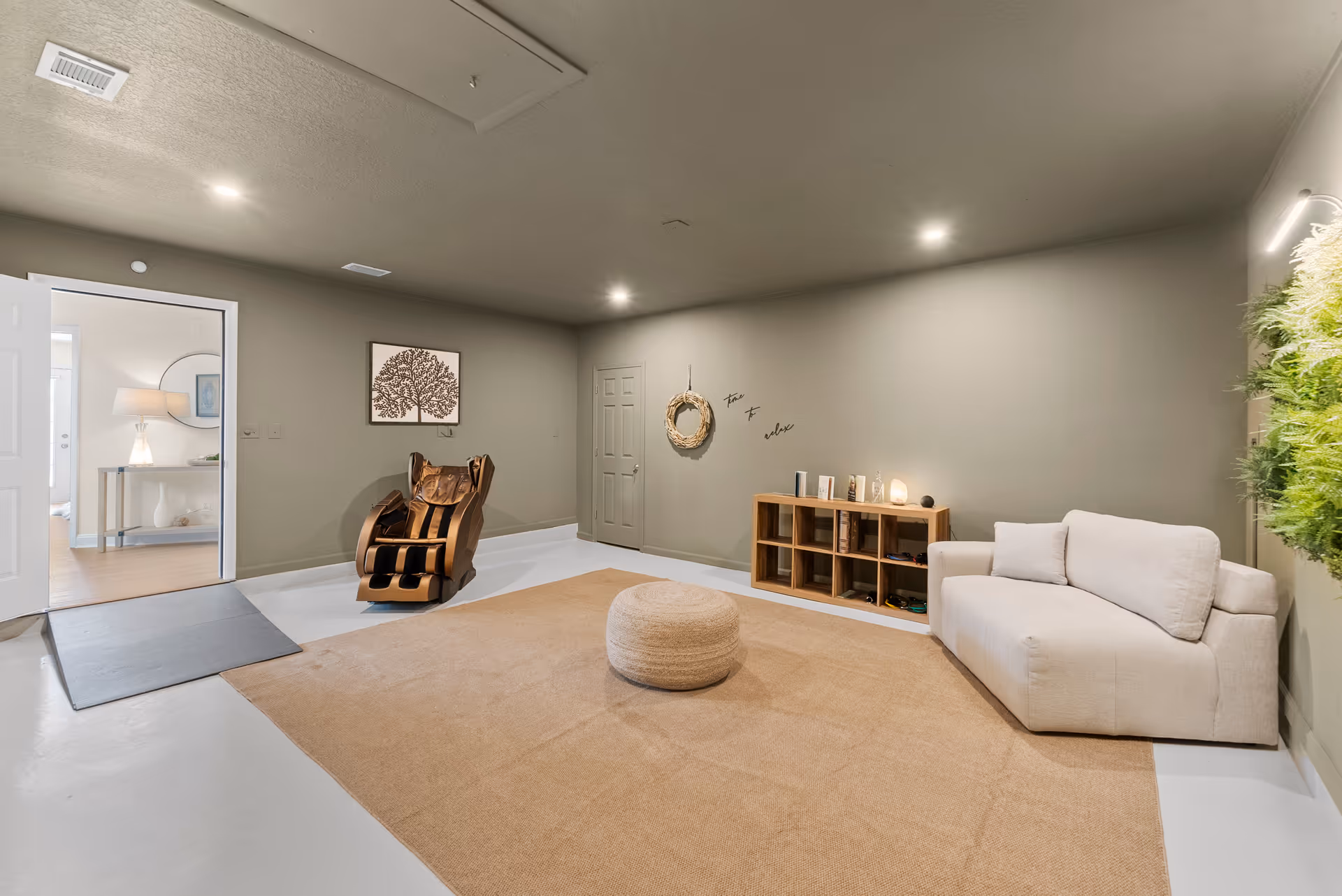 Cozy modern living room with beige sofa, rug, and massage chair in calming setup.