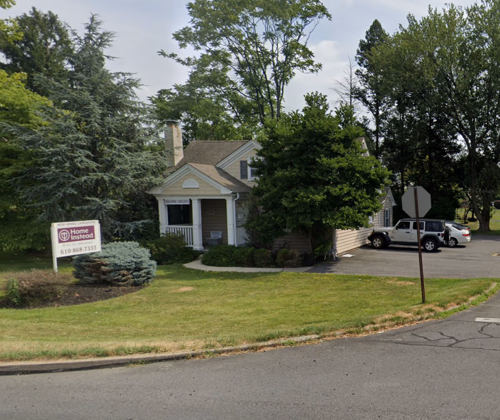 Front exterior of a Home Instead senior care building with sign and parked cars.