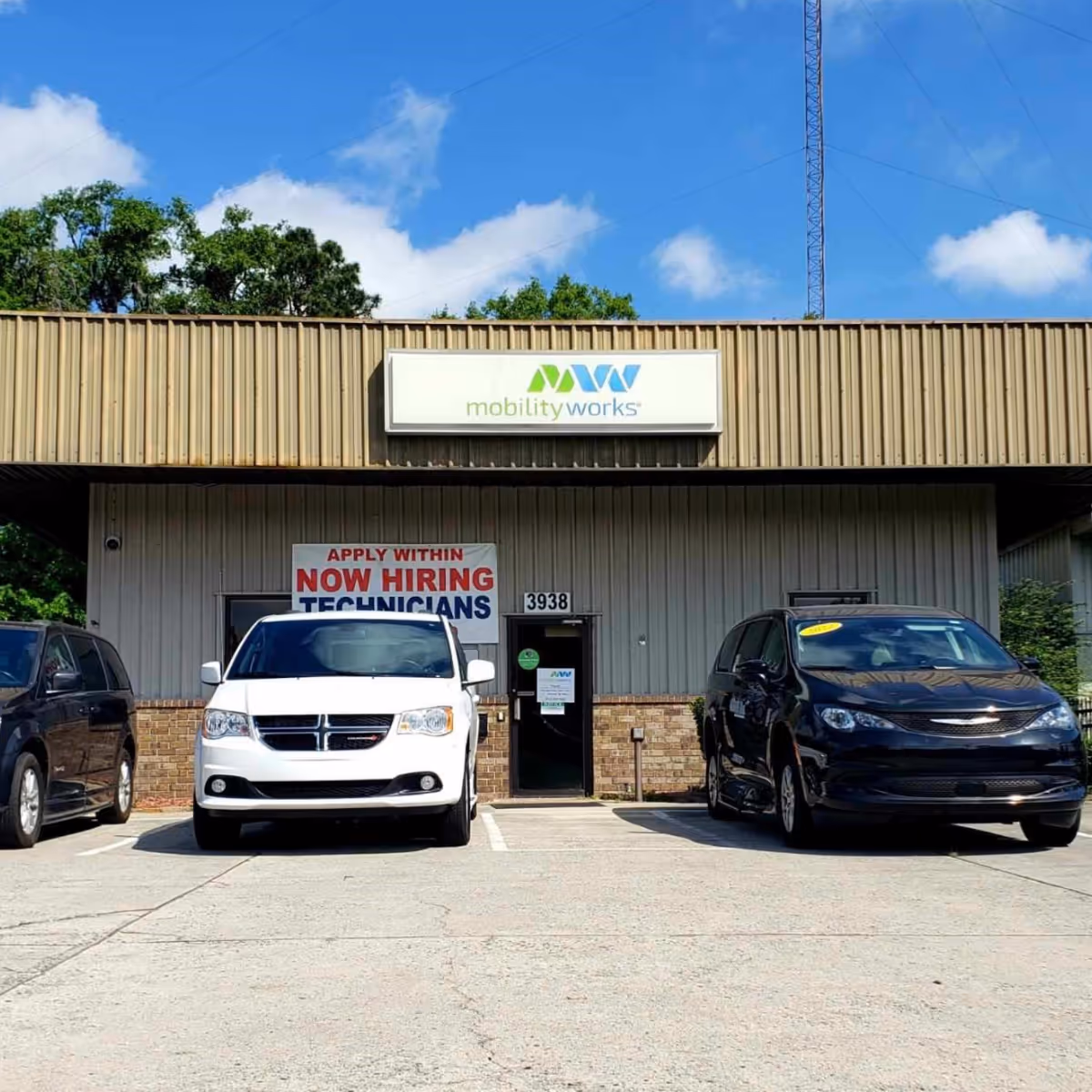Exterior view of MobilityWorks building with sign and parked vans in front.