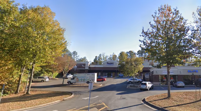 Exterior view of a Senior Helpers building with trees and a parking lot.