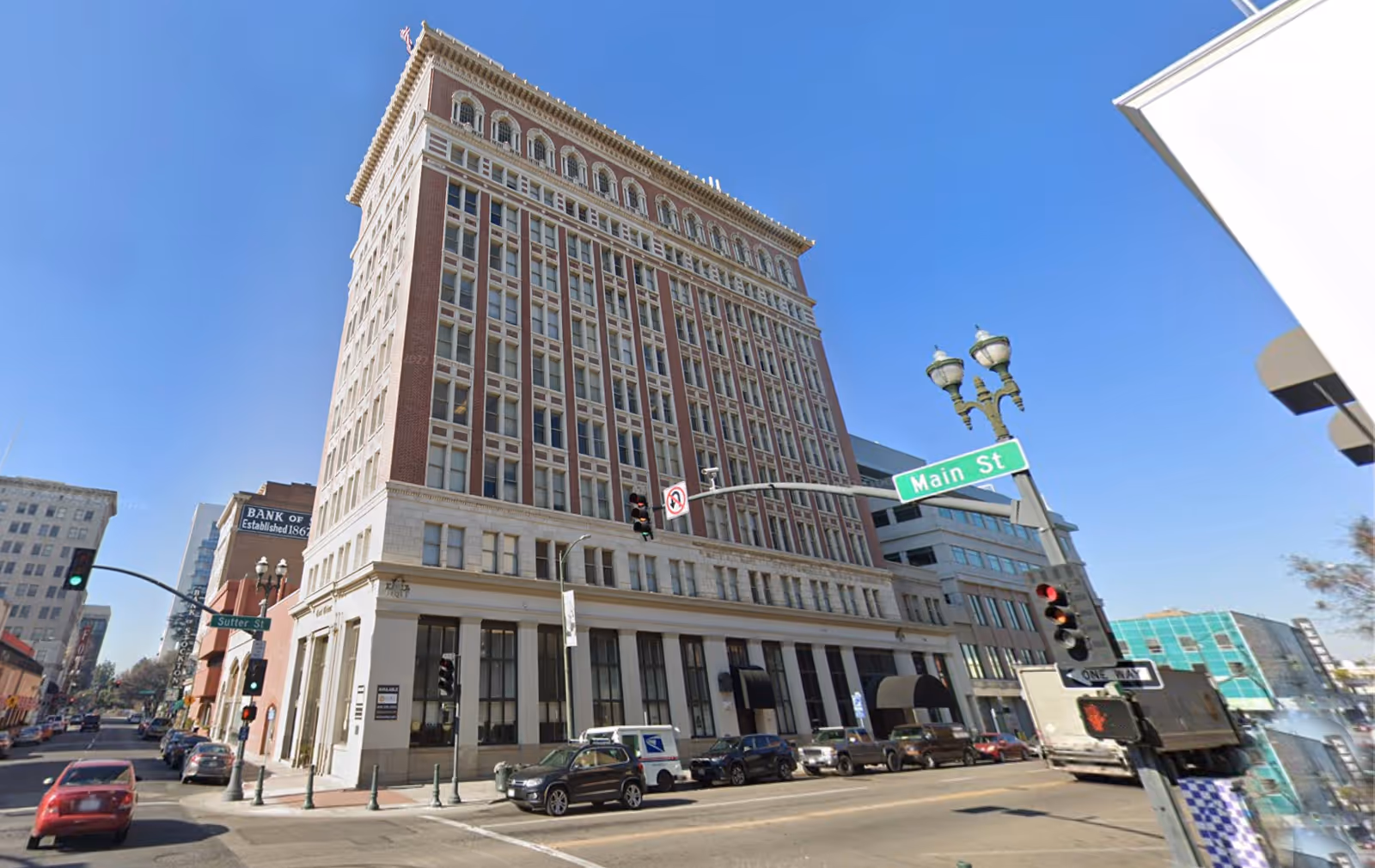 Corner view of a tall brick building on Main Street against a clear blue sky.