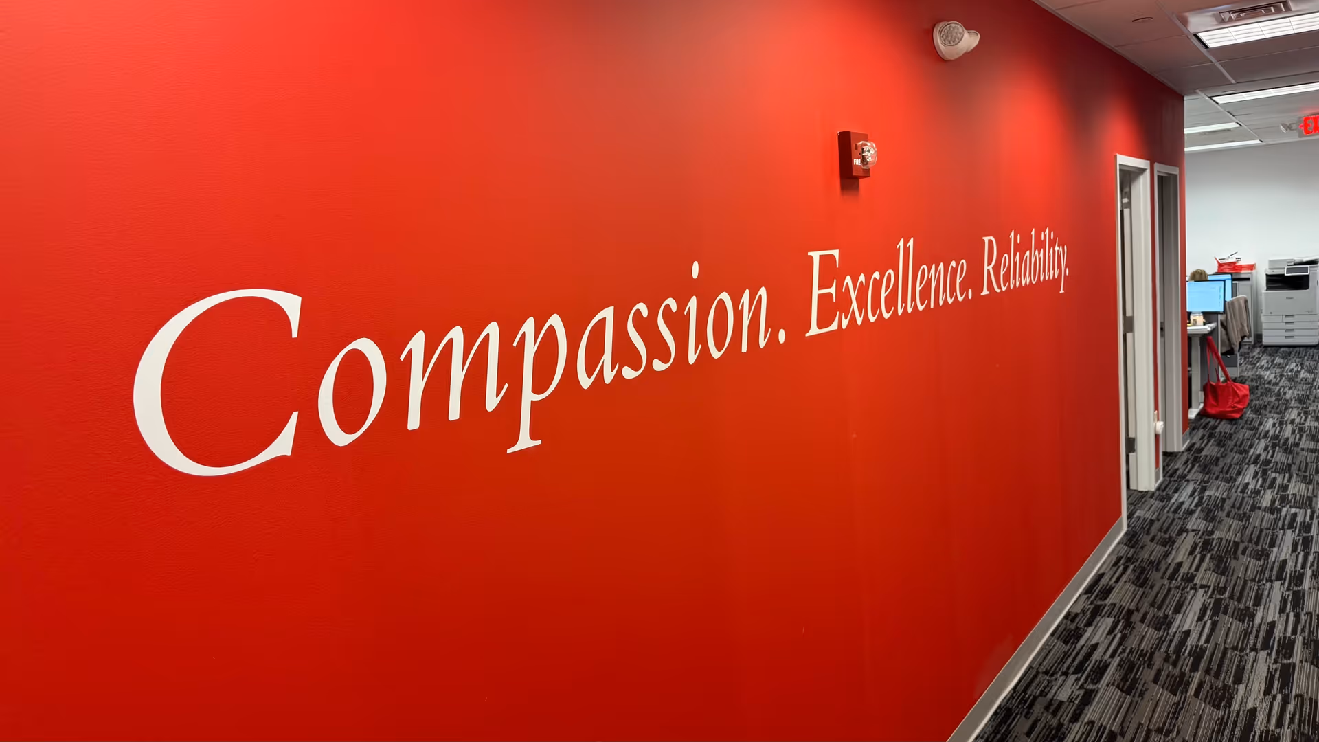 Red interior hallway with a large white slogan: Compassion. Excellence. Reliability. along the wall.