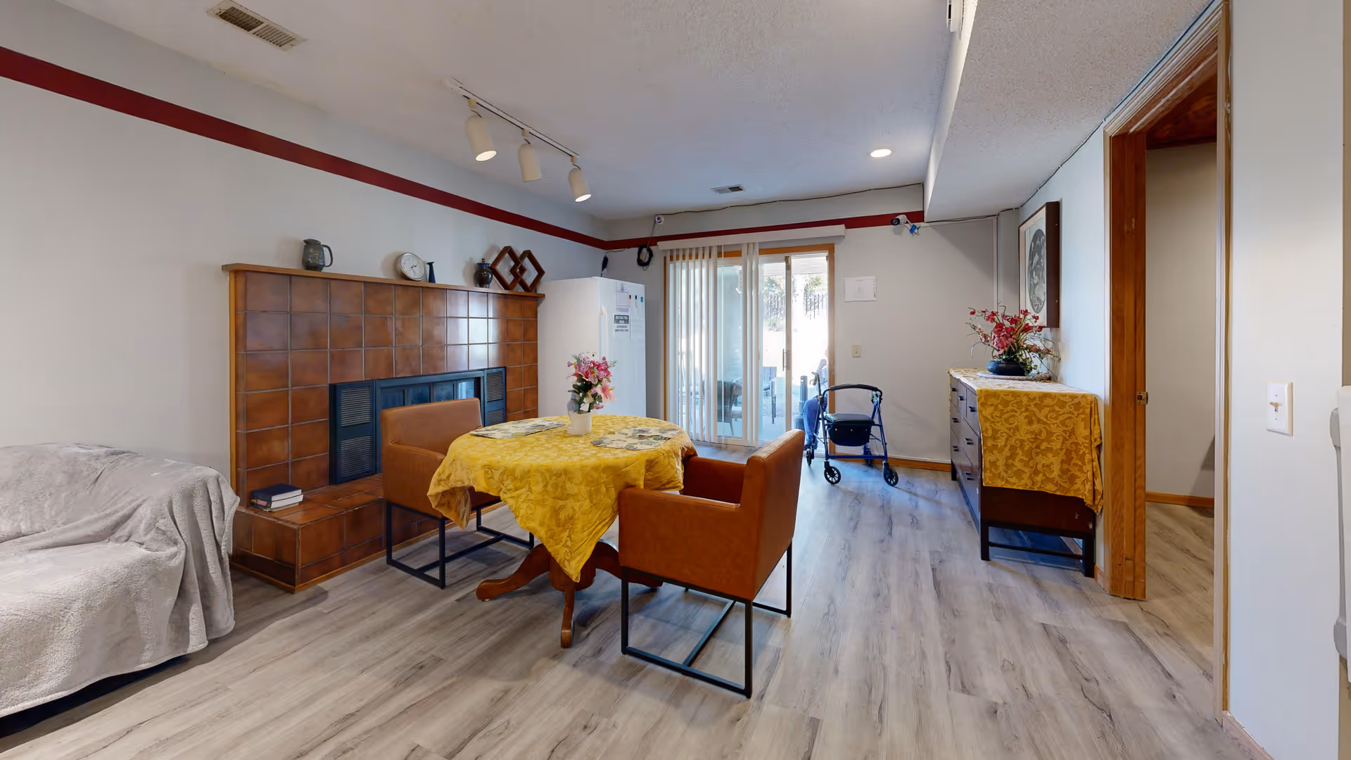 Cozy senior living room with fireplace, dining table, and sliding doors to a patio.