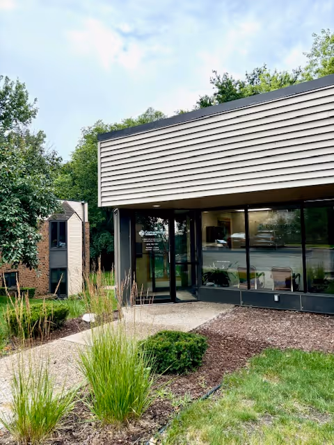 Modern senior care building exterior with glass entrance and landscaped front yard.