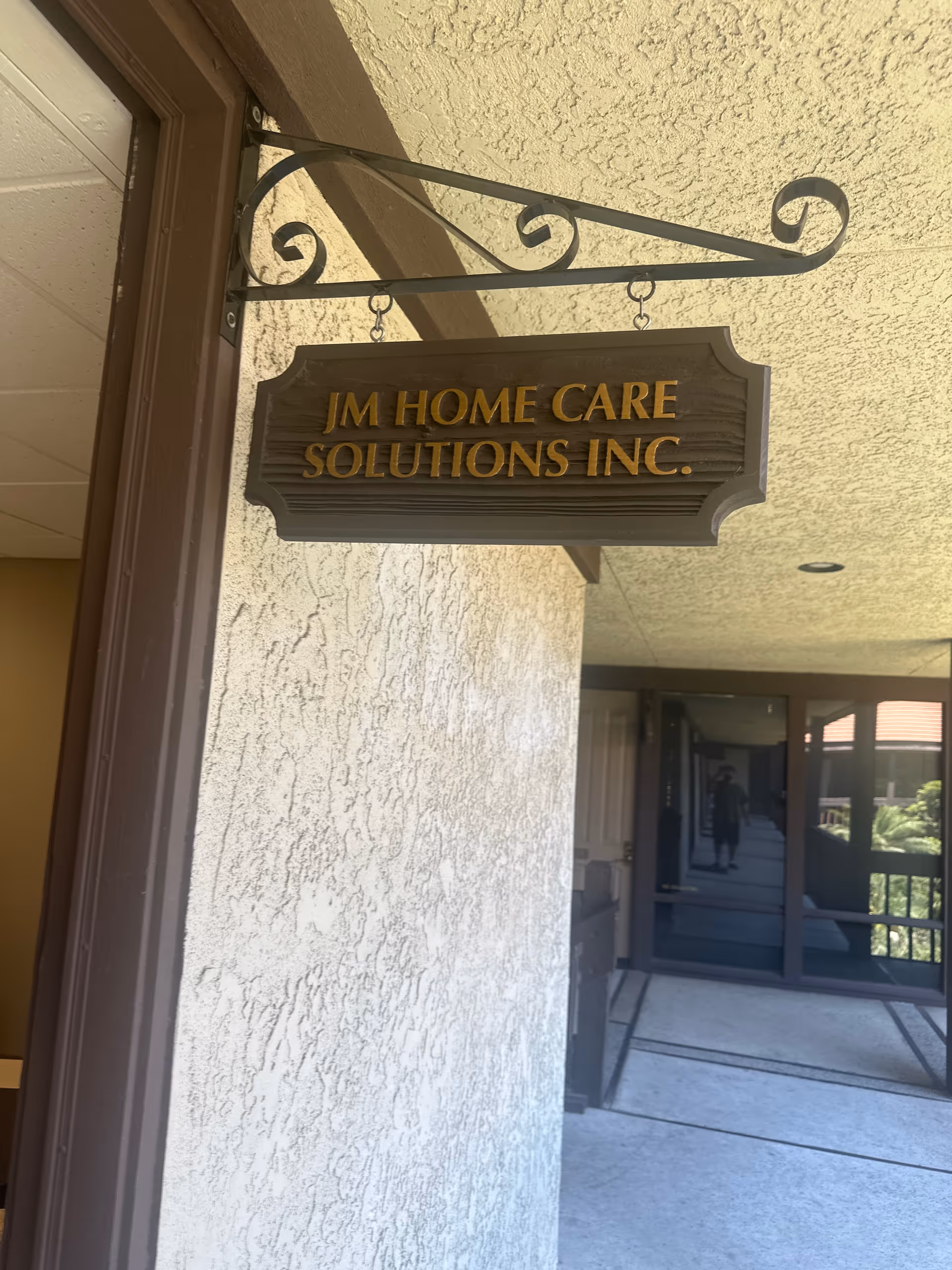 Exterior view of a facility entrance with a hanging JM Home Care Solutions sign.