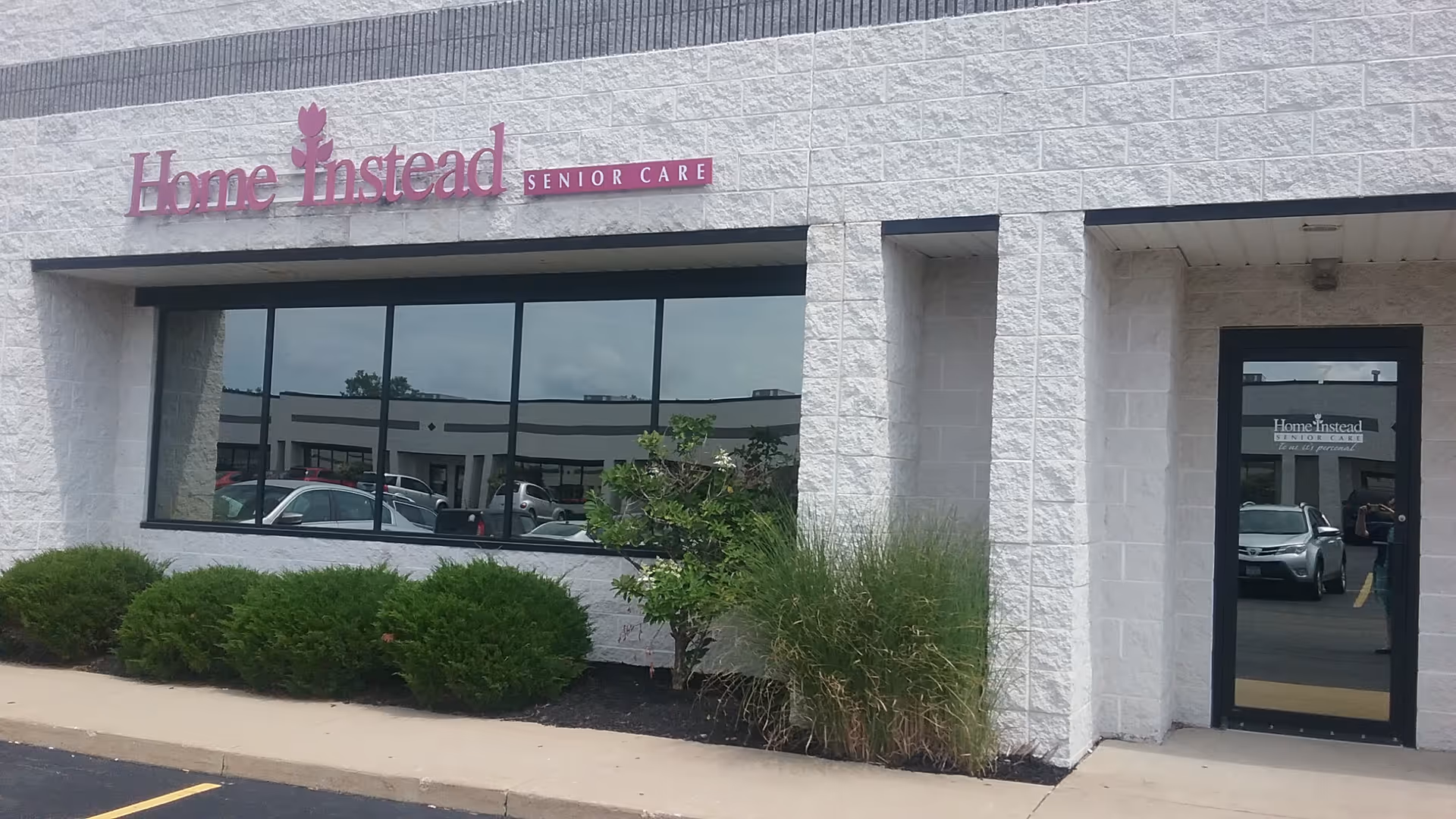 This is the Home Instead Senior Care storefront with a pink sign and large front windows.