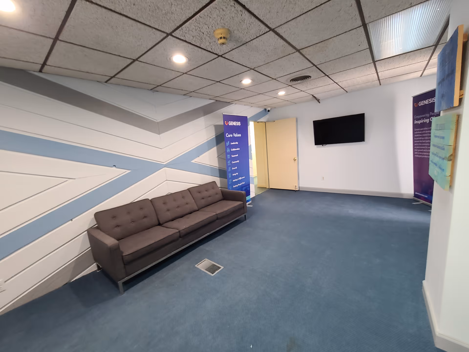 Blue carpeted lobby hallway with a long gray sofa and banners.