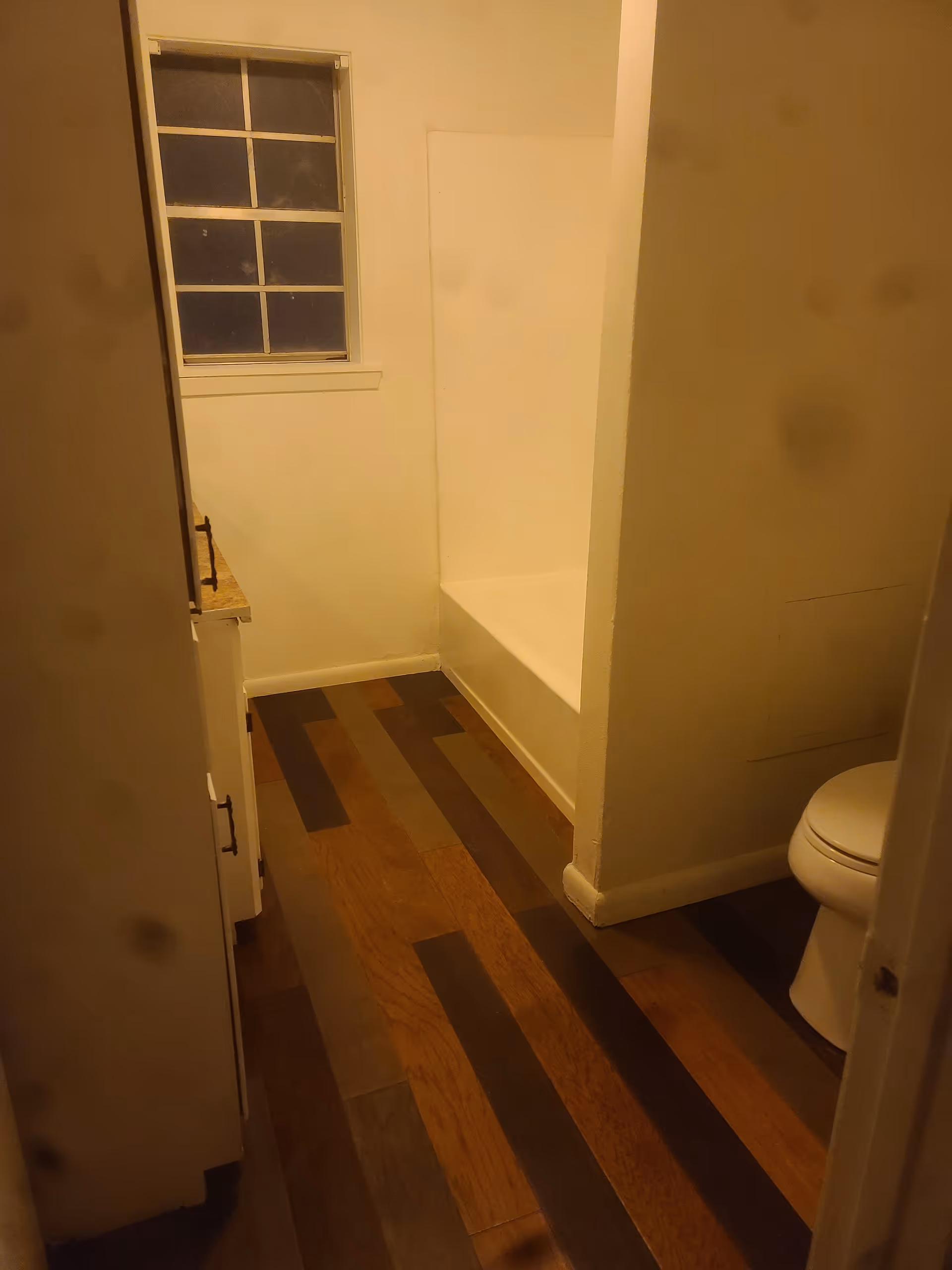 Narrow bathroom with a window, tub alcove, and toilet.