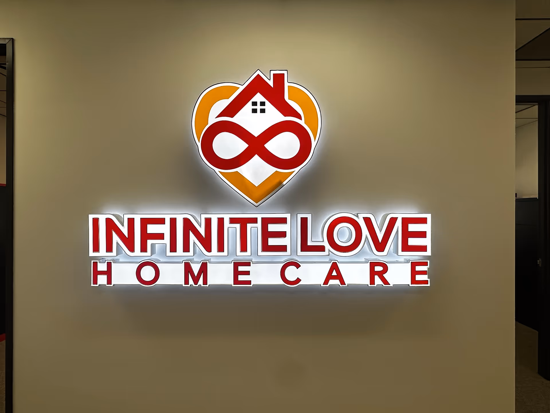 Interior wall with illuminated Infinite Love Homecare logo and sign text.