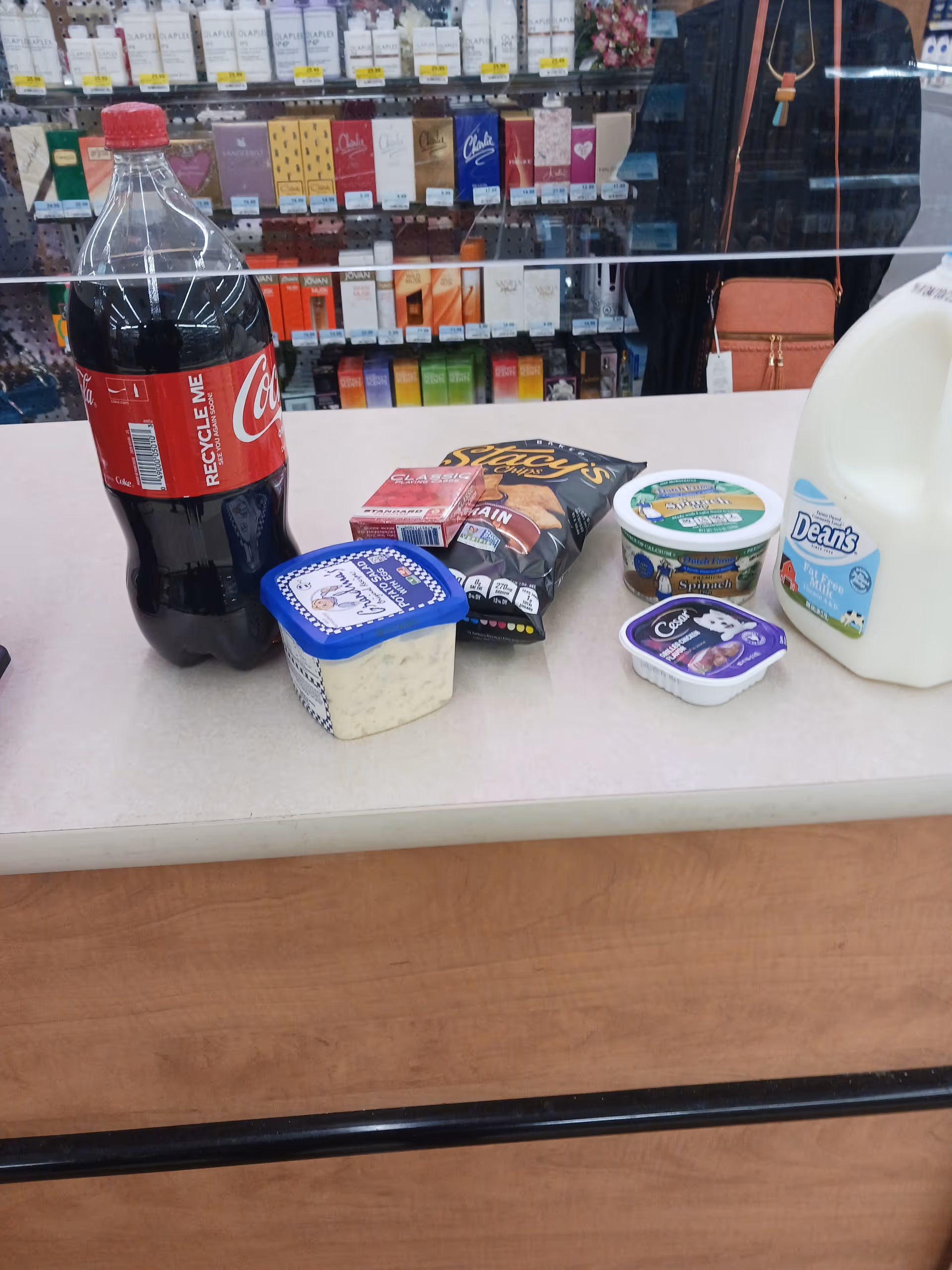A Coca-Cola bottle and assorted dairy products sit on a store checkout counter.