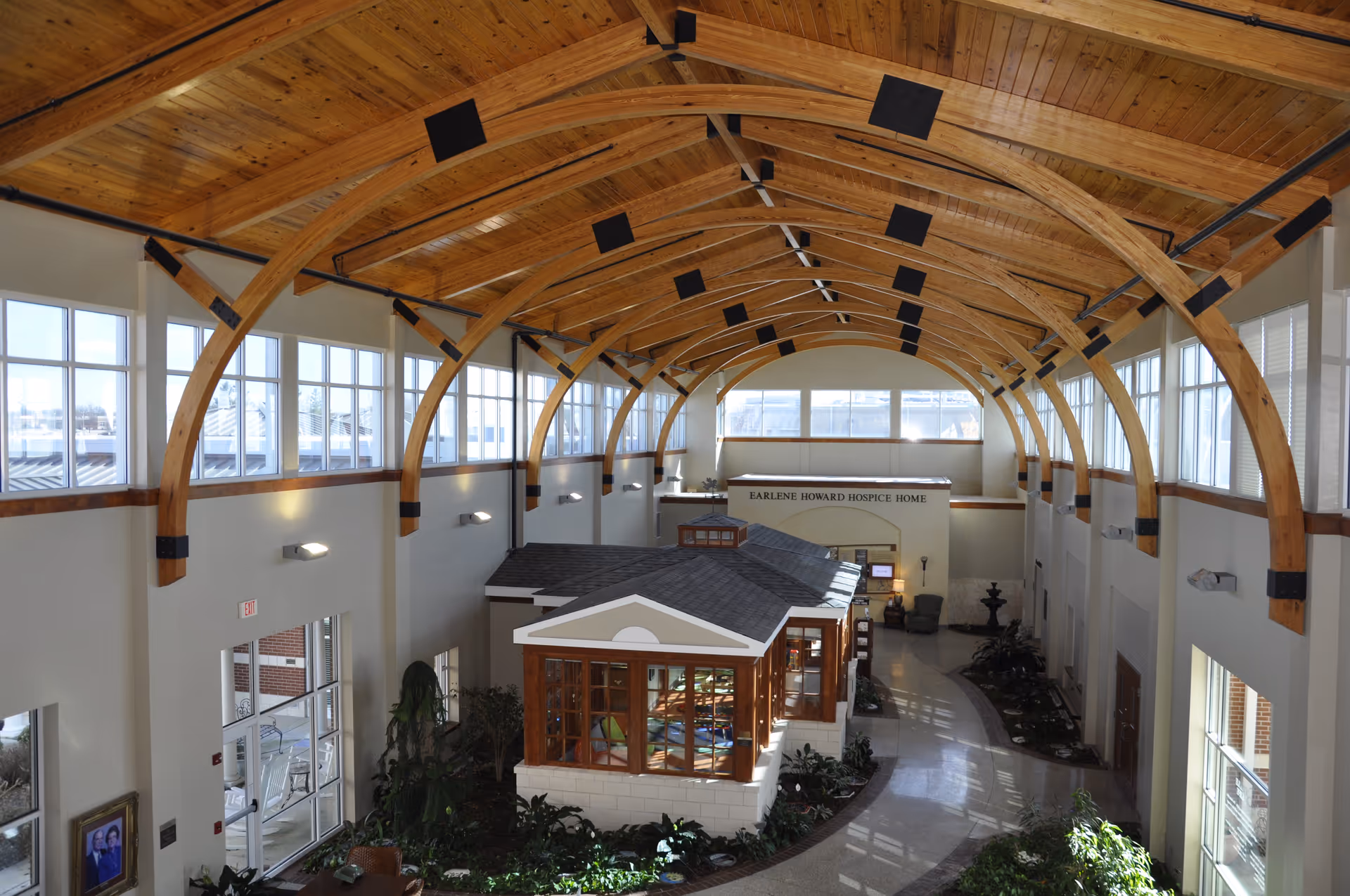 Interior atrium of hospice facility with arched wooden ceiling and glass windows.