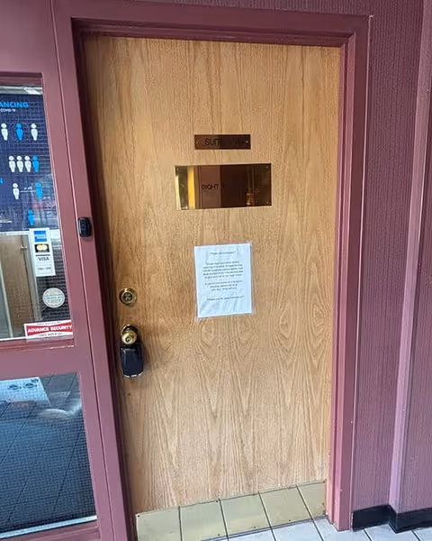 Wooden interior door with small windows and a posted notice in a purple hallway.