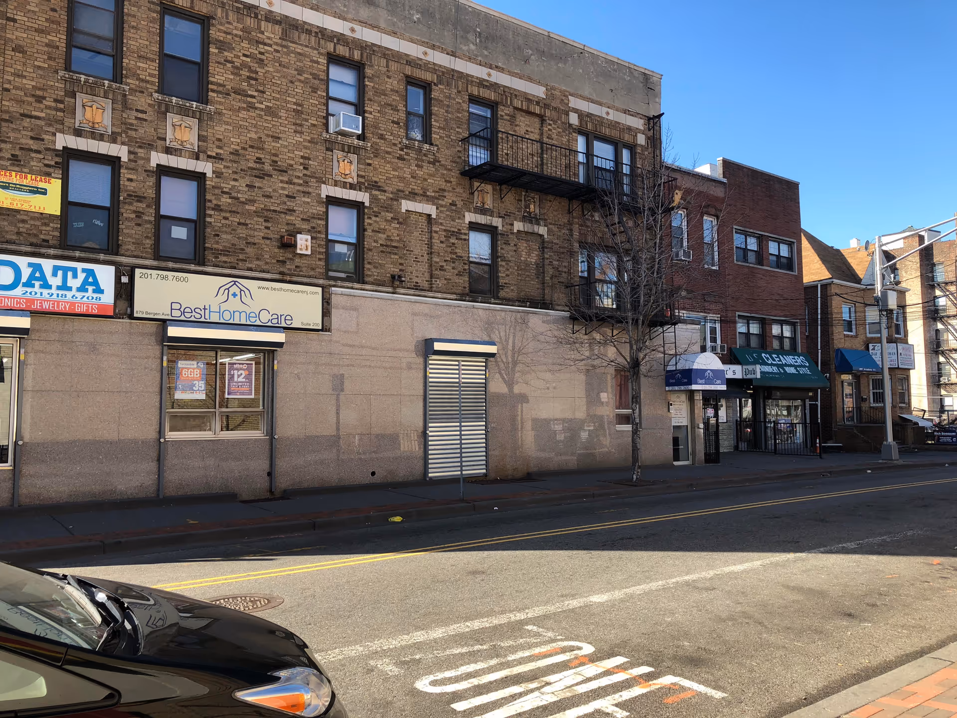 City street storefronts with a brick building and a Best Home Care sign.