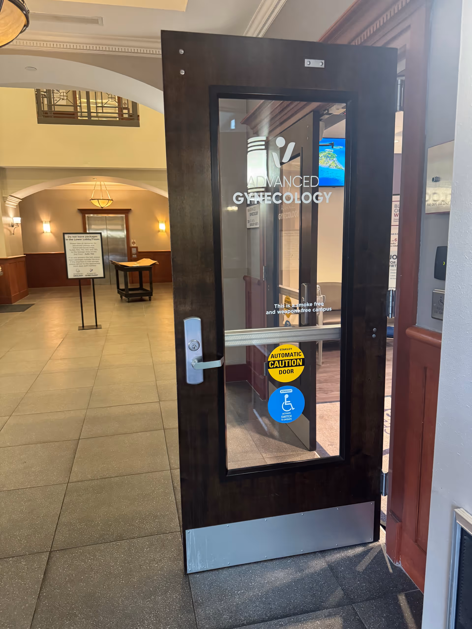 Dark wooden glass door labeled Advanced Gynecology opens into a spacious lobby.