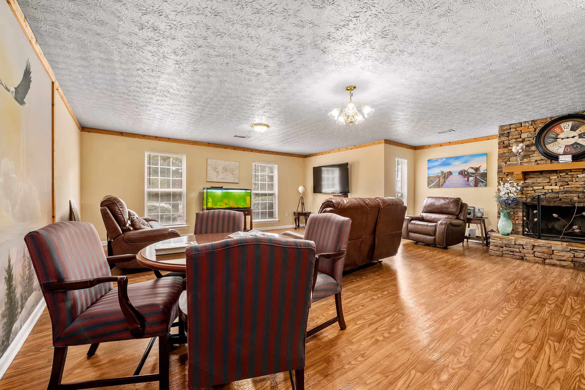 Living room in a senior care home with sofas, chairs, a TV, and a fireplace.