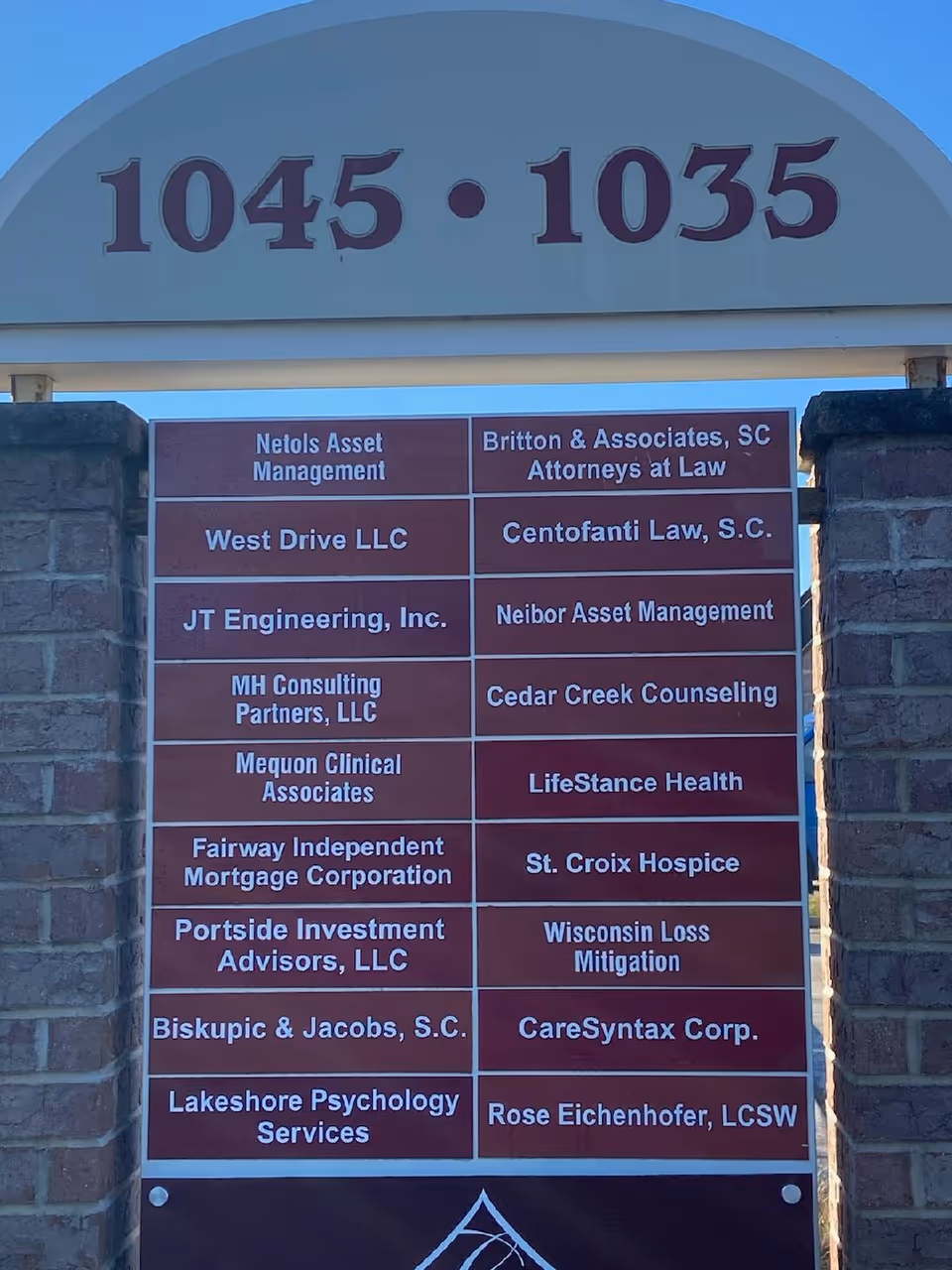 Exterior entrance with brick arch and a large plaque listing tenants.