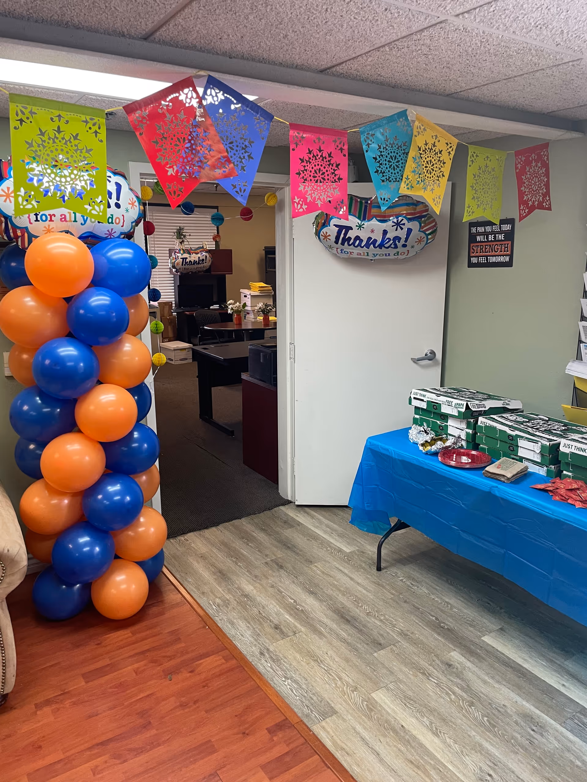 Colorful banners, balloons, and a blue-covered table decorate an interior facility area.