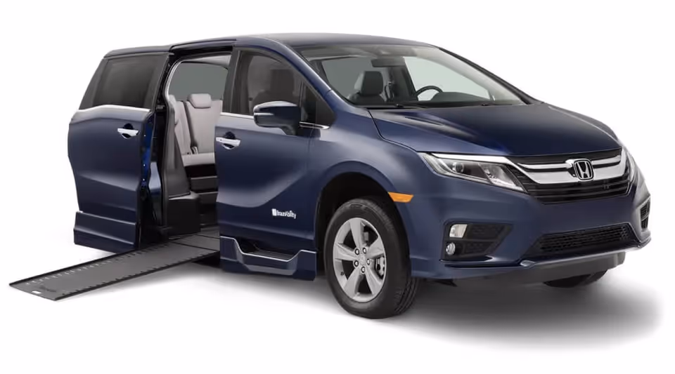Blue wheelchair-accessible minivan with ramp extended, shown from the side.