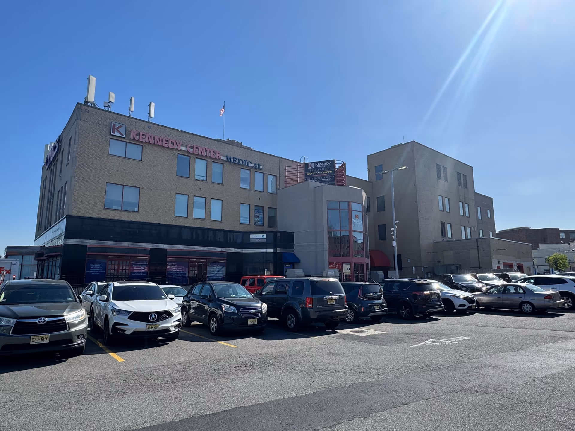 Exterior view of a large medical building with a parking lot and blue sky.