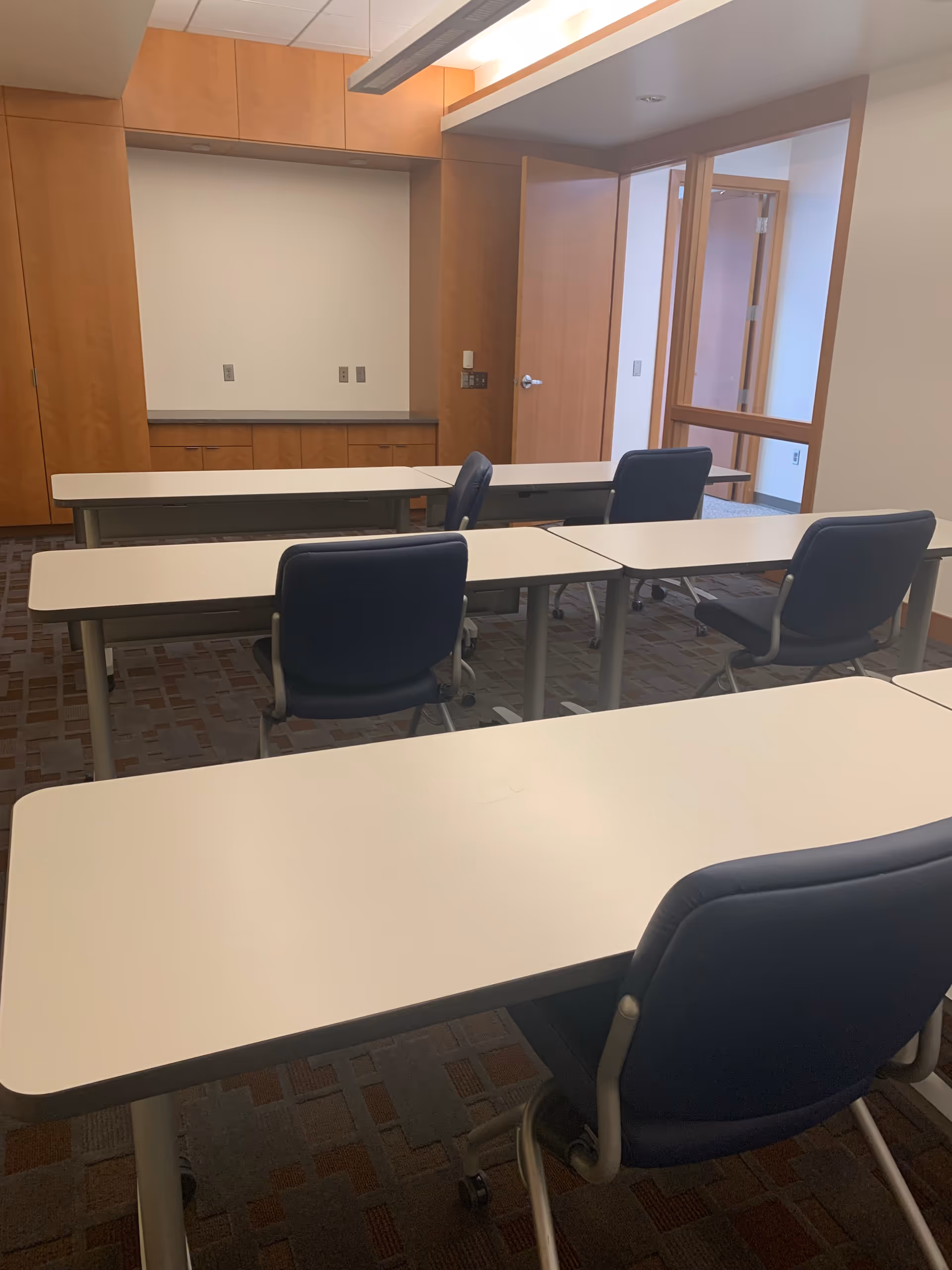 Classroom-style room with white tables and blue chairs inside a facility.
