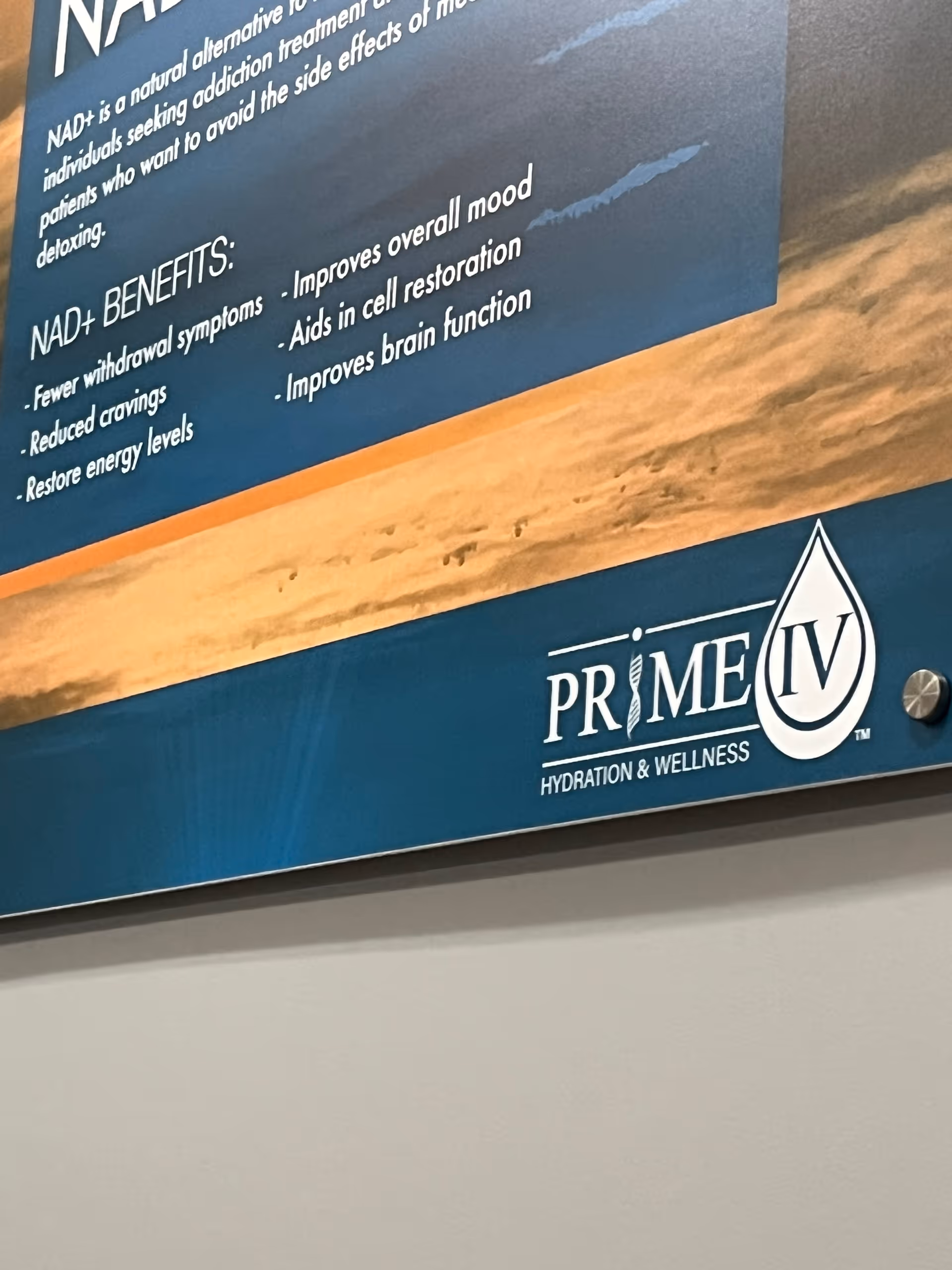 Blue wall sign displays Prime IV Hydration & Wellness logo and NAD+ benefits.