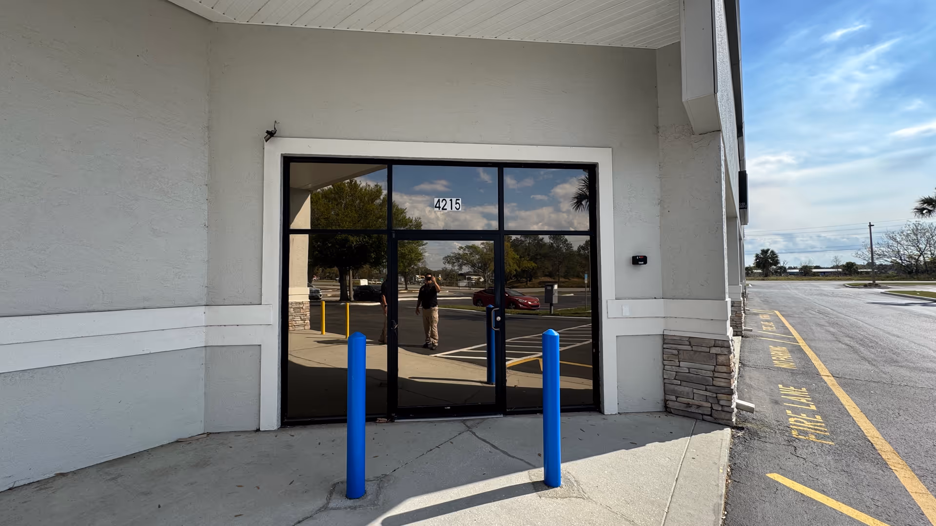 Exterior view of Cornerstone Hospice entrance with glass doors and blue bollards.