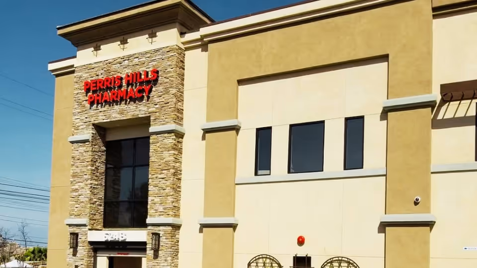 Exterior view of Perris Hills Pharmacy storefront with beige walls and stone accents.