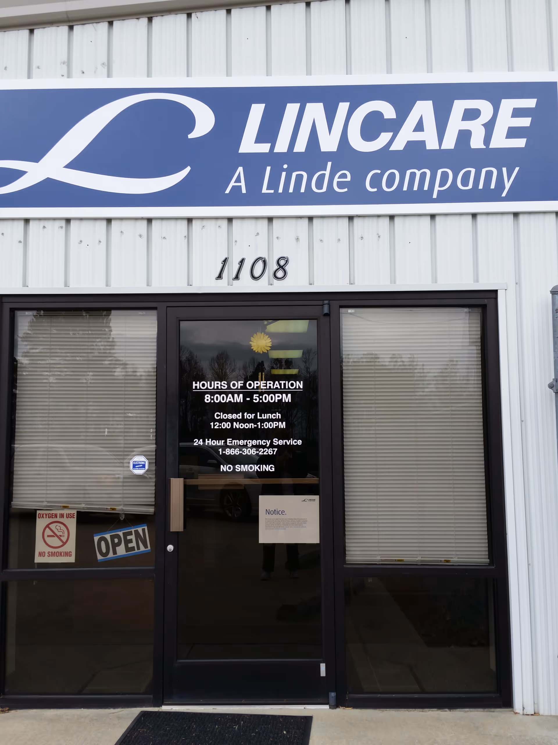 Front entrance of a LINCARE building with glass doors and operating hours sign.