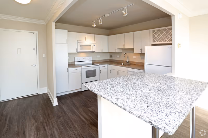 Bright kitchen with white cabinets, appliances, and a granite island.