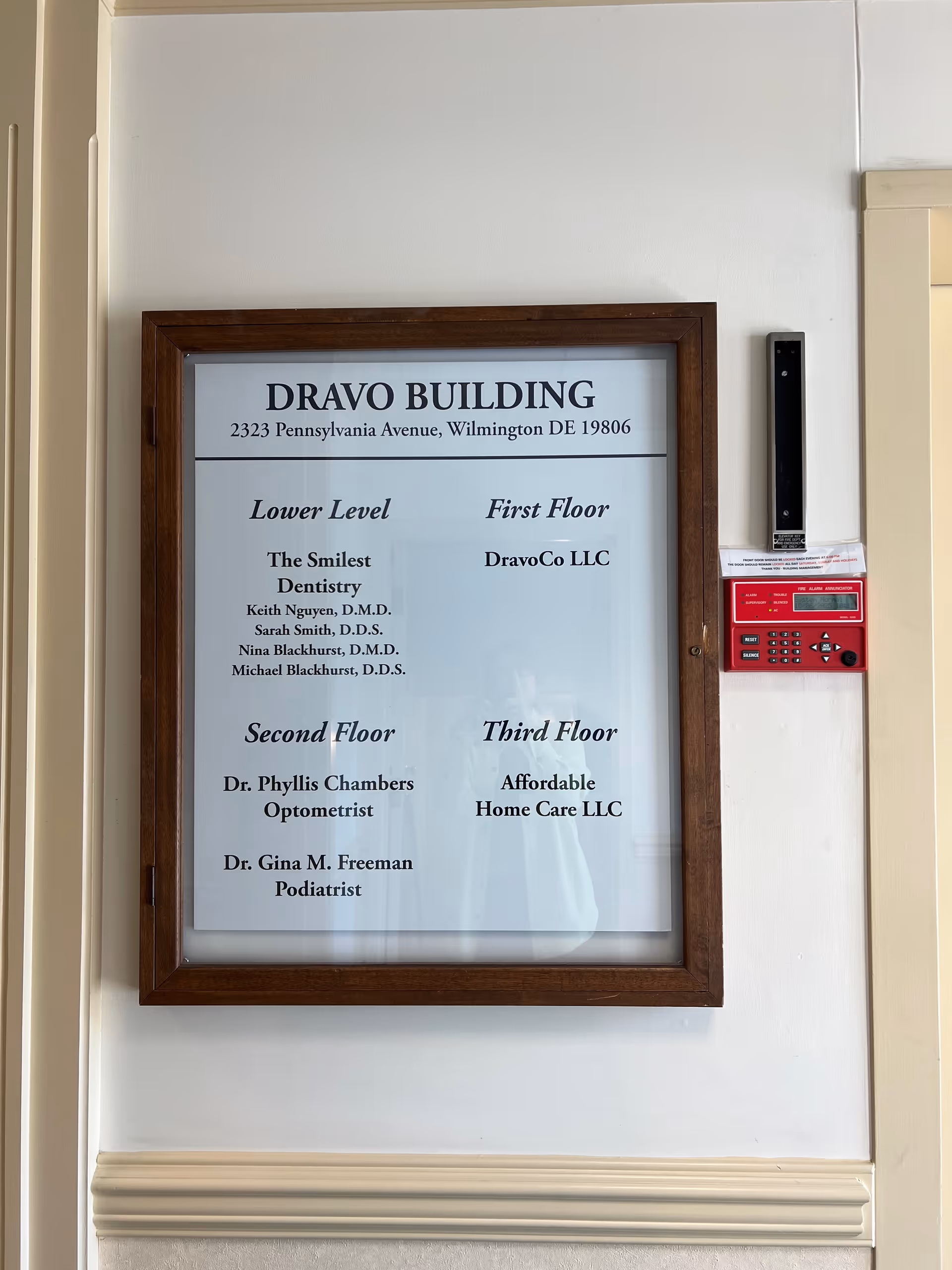 Framed building directory on interior wall listing floors and tenant names.