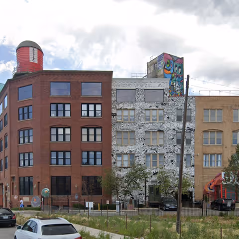 Exterior view of three urban buildings with mosaic facade beside a street.