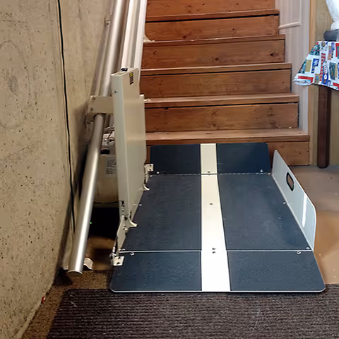 Indoor stair lift installed along a wooden staircase inside a senior living facility.