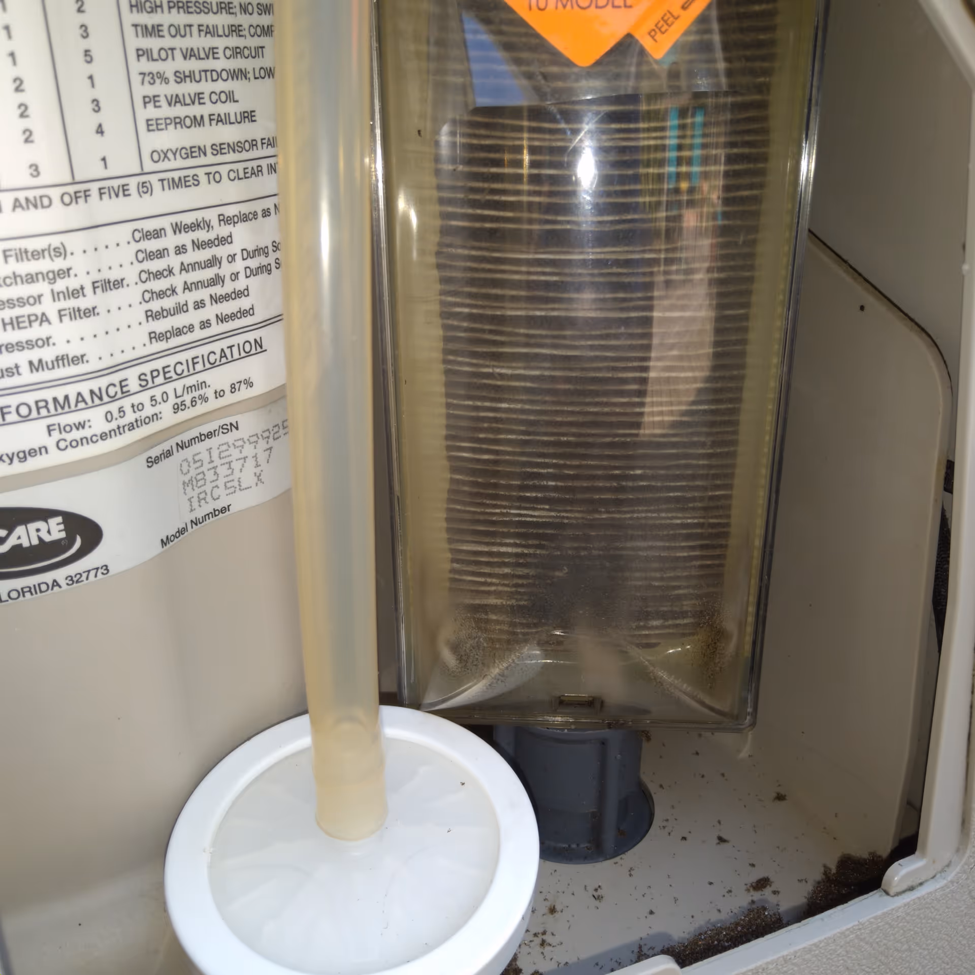 Close-up of a medical oxygen concentrator and humidifier bottle inside a cabinet.