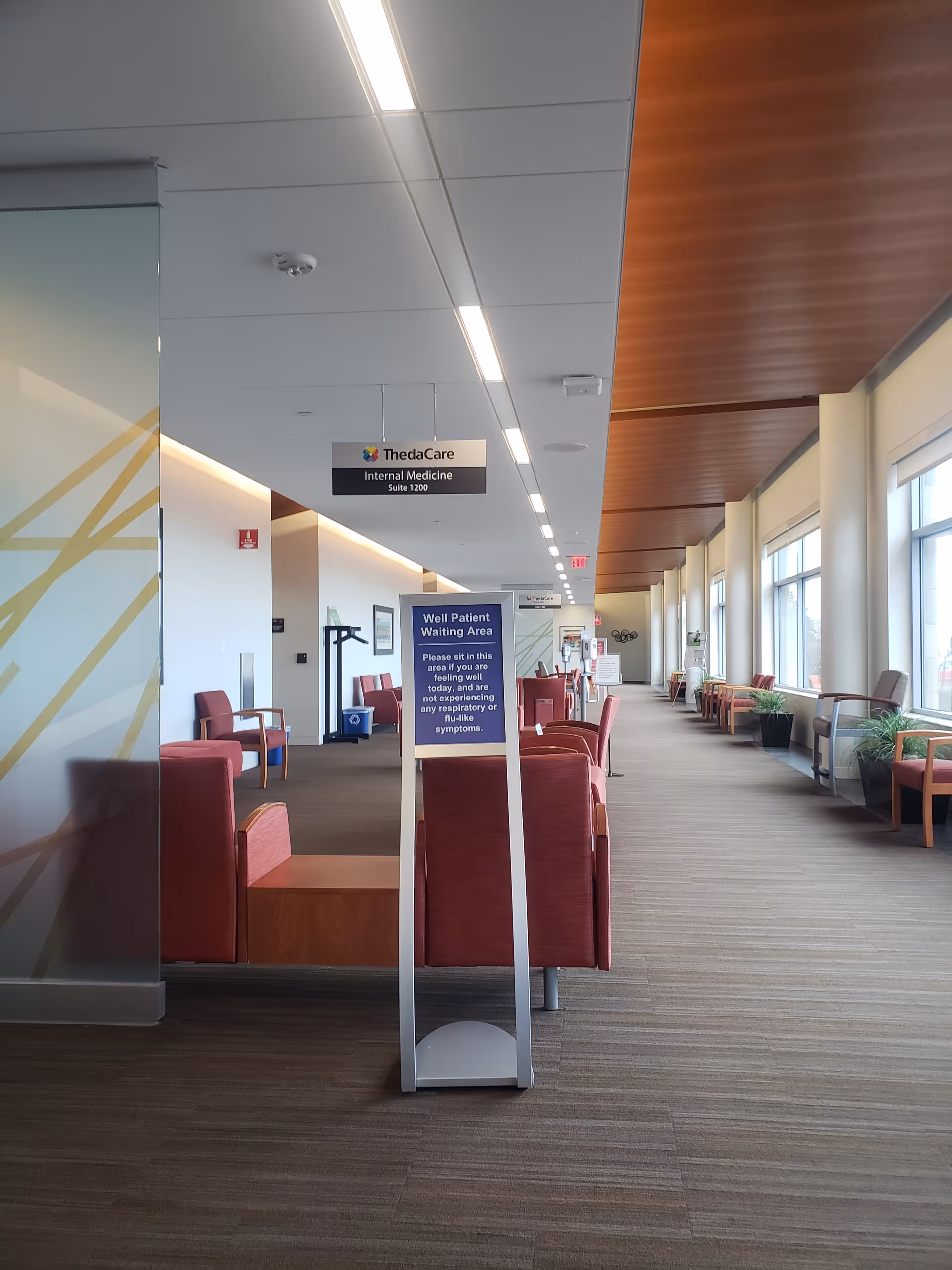 Interior hallway of Encircle Health with red seating and a waiting area sign.