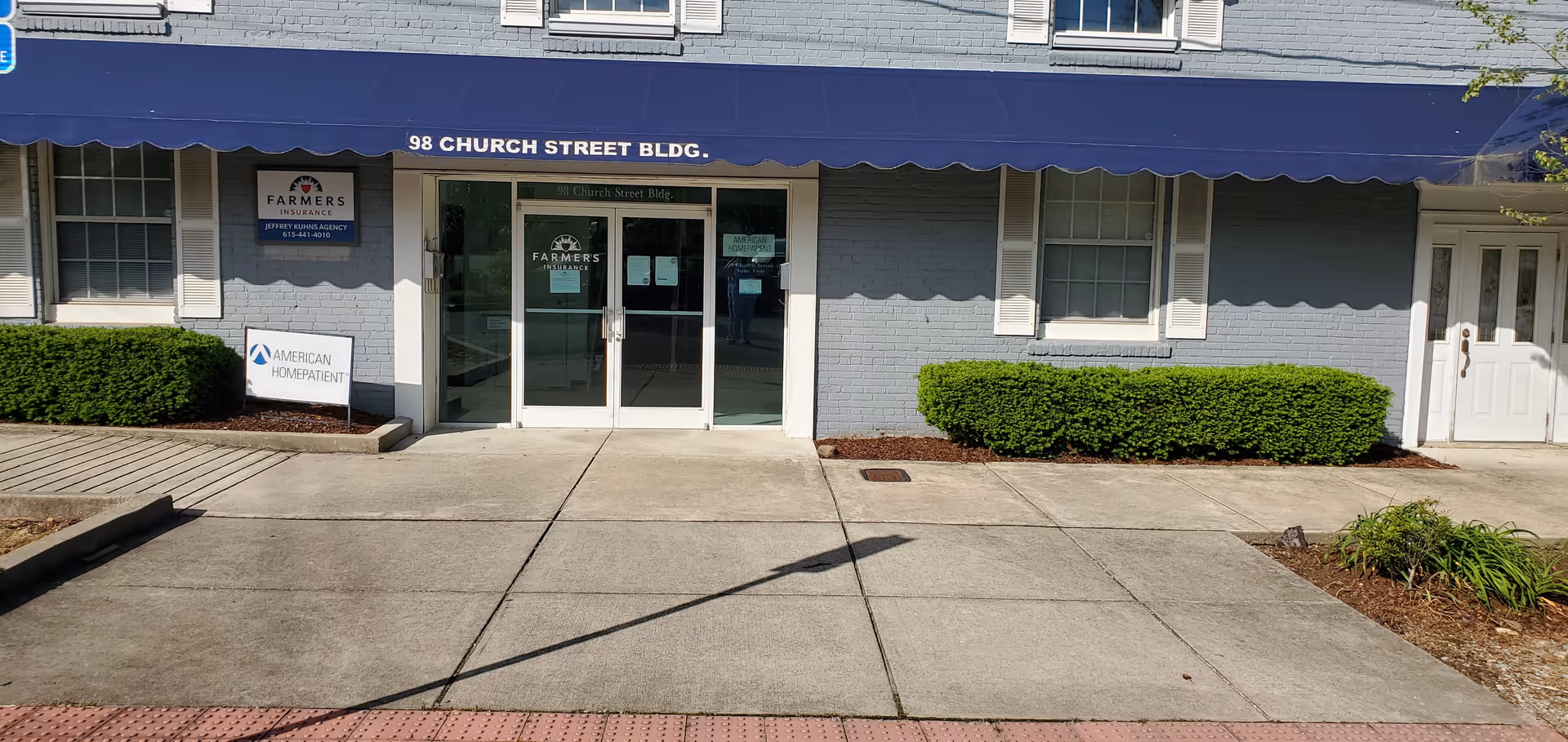 Exterior view of a building entrance with blue awning and American HomePatient signage.