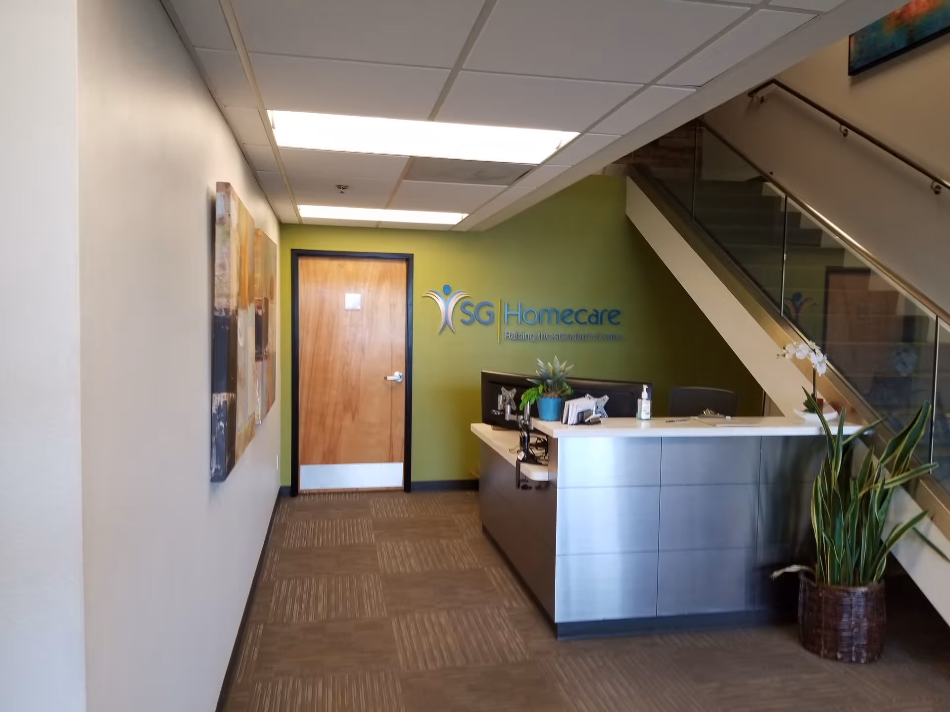Indoor reception area with a curved desk, stairs, door, and green accent wall.