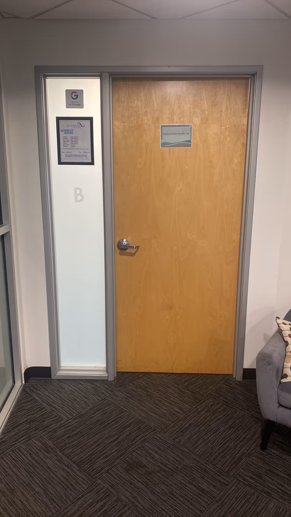 Interior hallway with wooden door, frosted glass panel, and posted signs.